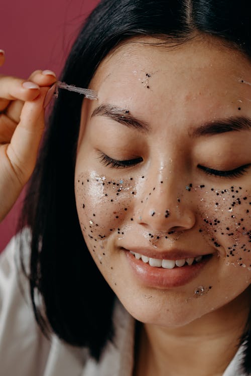 A Close-up Shot of a Woman Peeling a Glitter Mask on Her Face