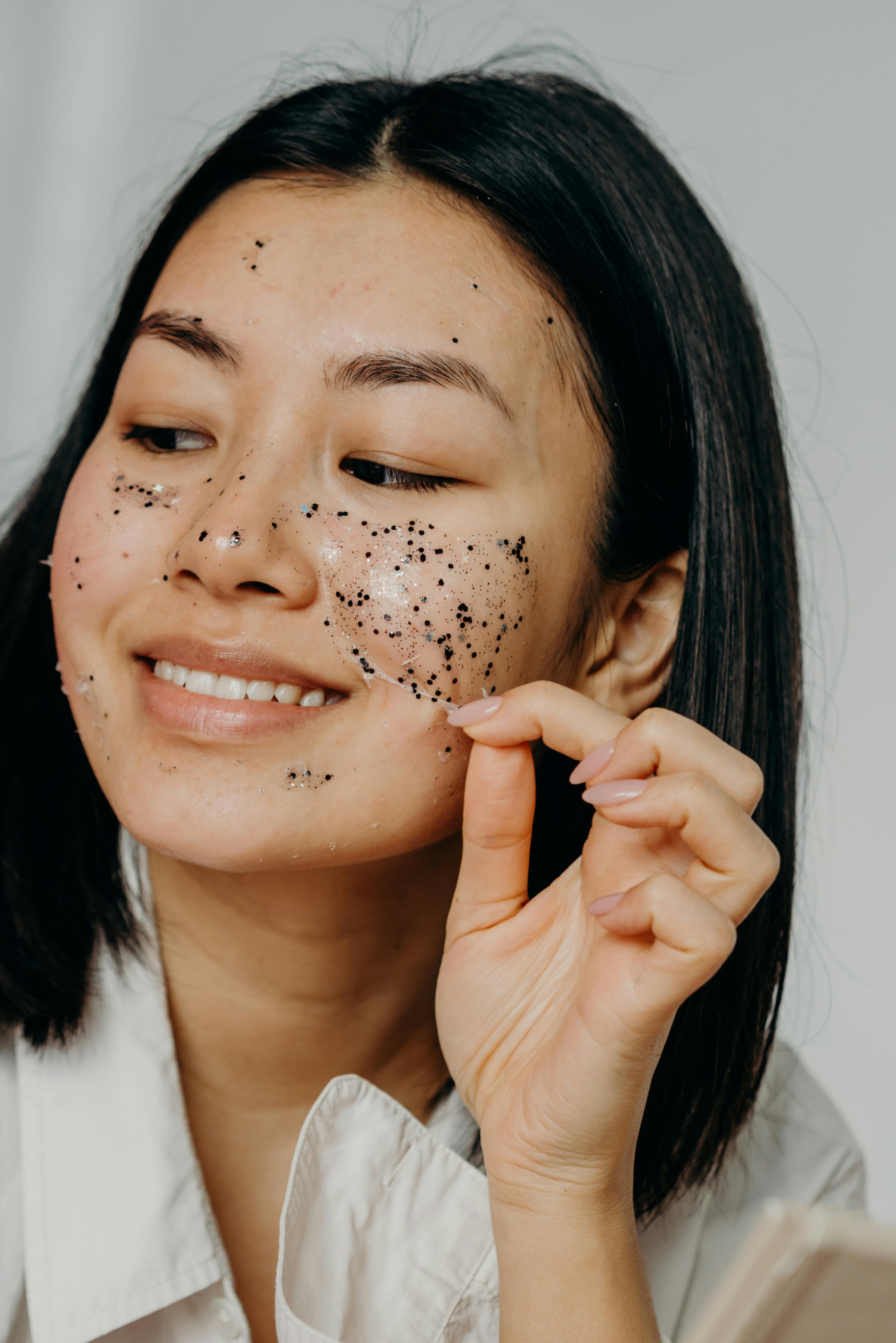 A Smiling Woman Peeling a Glitter Mask on Her Face · Free Stock Photo