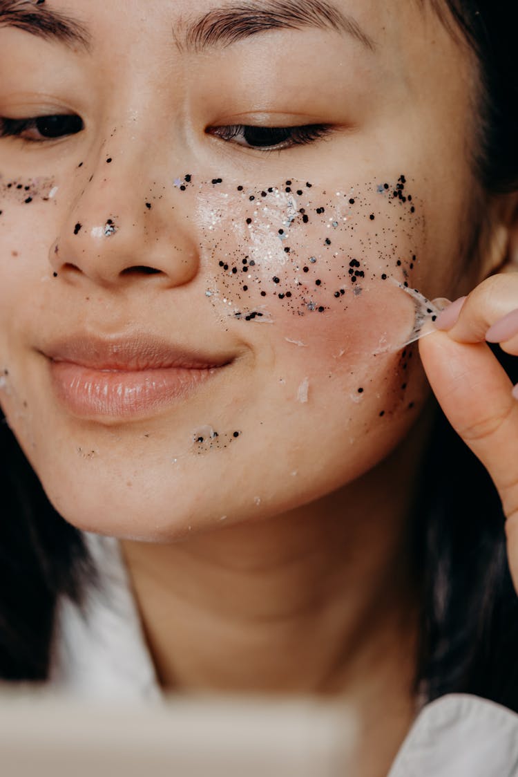 A Woman Peeling A Glitter Mask On Her Face
