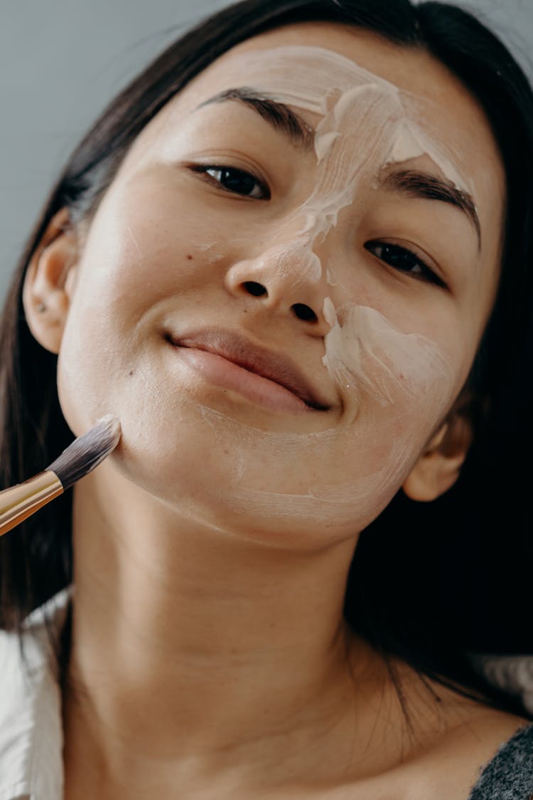 A Woman Applying A Cream On Her Face