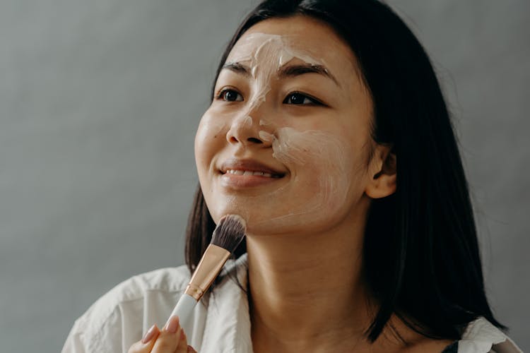 A Woman Applying A Cream On Her Face