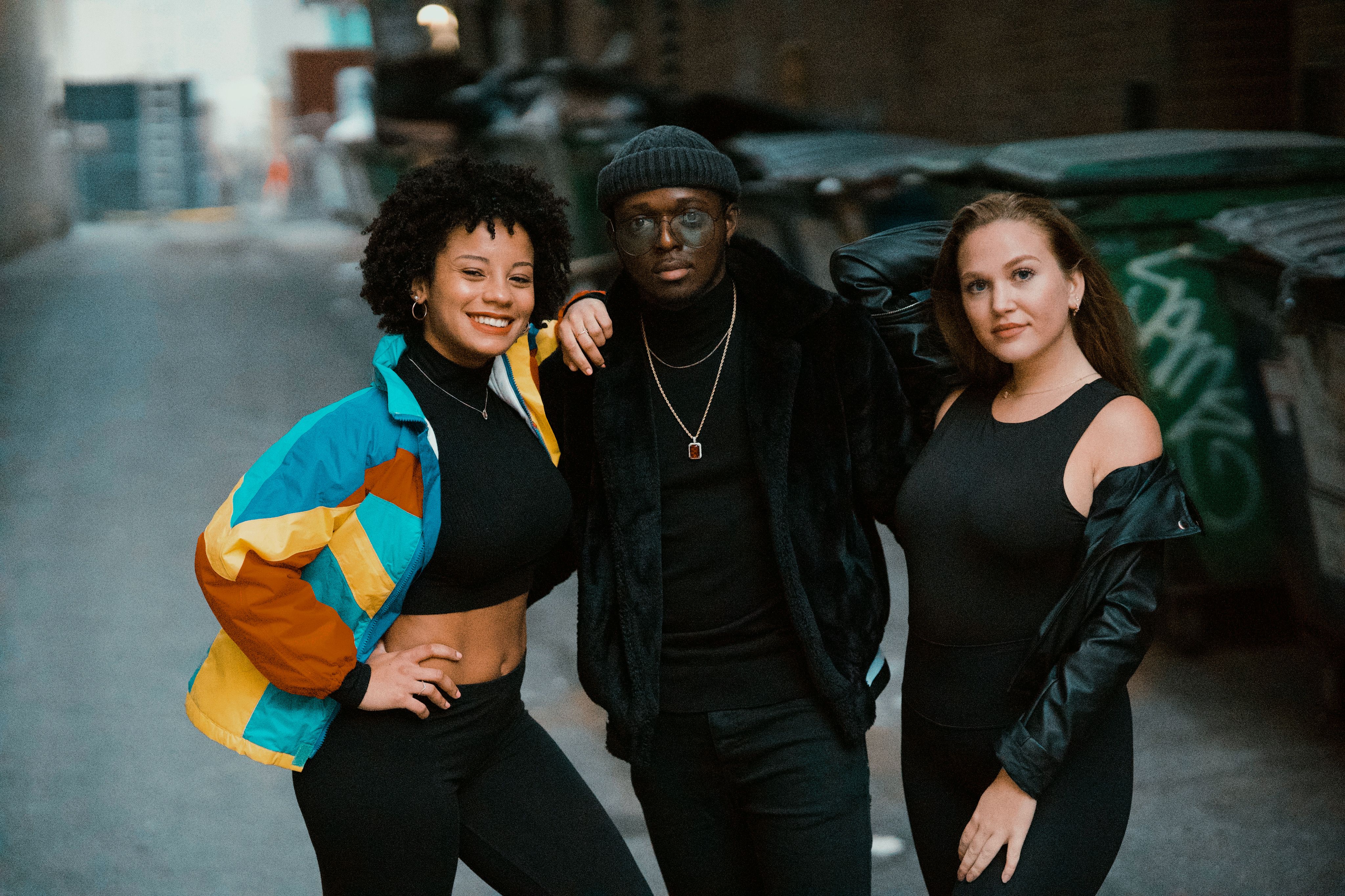 A Man in Black Clothes Standing Between the Women Smiling on the Street ...