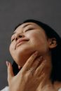 A Woman Touching Her Neck with Her Eyes Closed