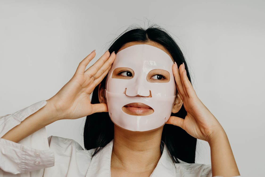 Woman applying a hydrating overnight sheet mask as part of her skincare routine