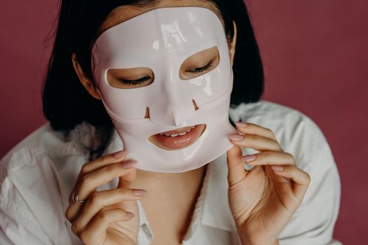 A Woman in White Shirt Peeling Her Facial Mask