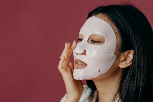 A Woman Touching Her Face with Sheet Mask