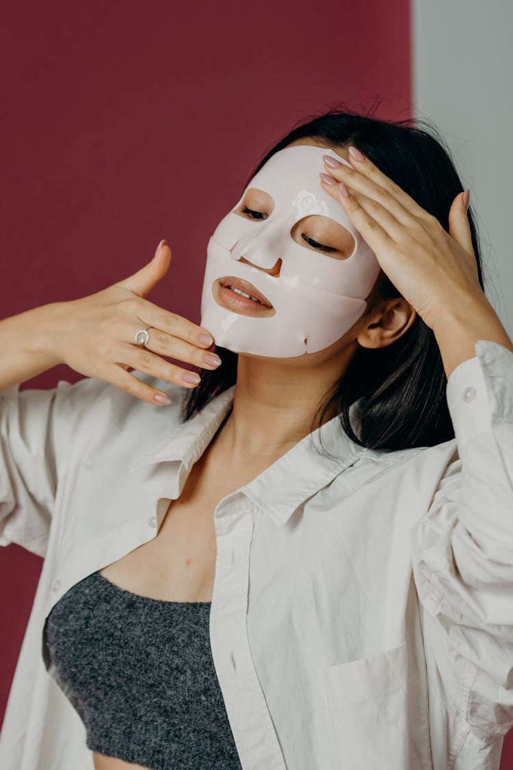 A Woman In White Long Sleeves Touching Her Face With Mask