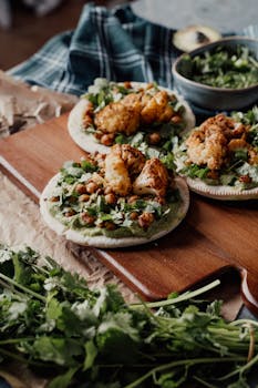 Tasty vegan tacos topped with grilled cauliflower and greens on a wooden board.