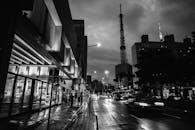 夜间城市景观以戏剧性的黑白风格呈现，突显了塔楼与街道活动的特色