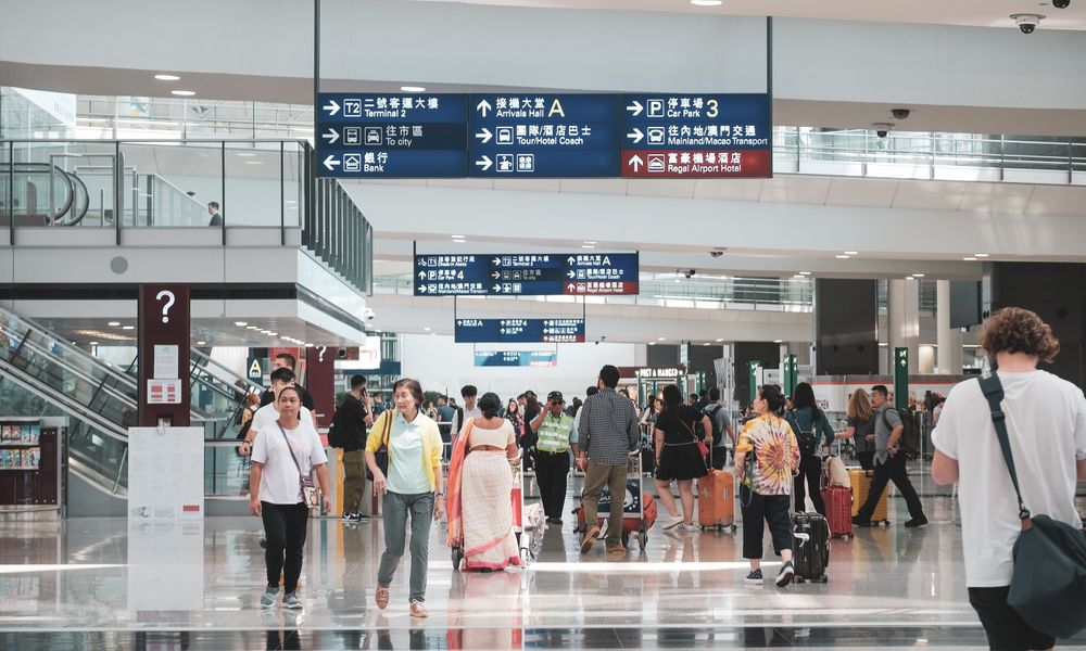 travelers reading a health alert board at an international airport