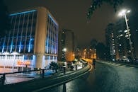 夜晚，一个孤独的人走在城市潮湿的街道上，周围是发光的建筑