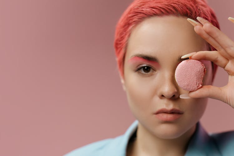 Woman With Pink Hair Holding A Pink Macaroon Against Her Eye 