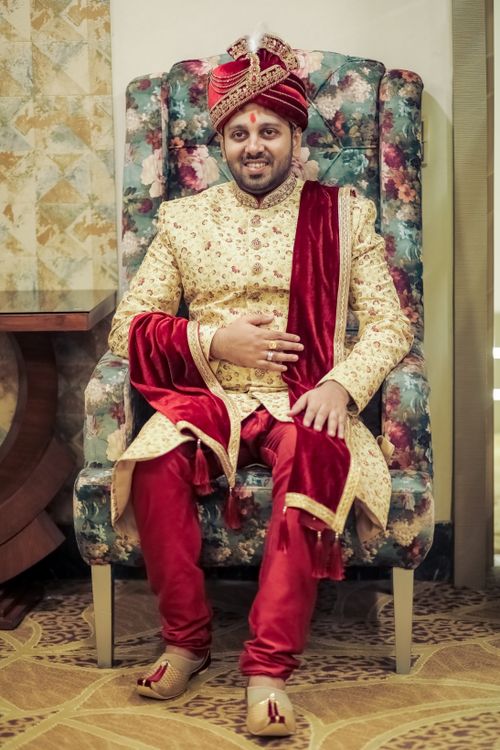 Free An Indian groom seated in ornate traditional attire with a turban and rich red textiles. Stock Photo