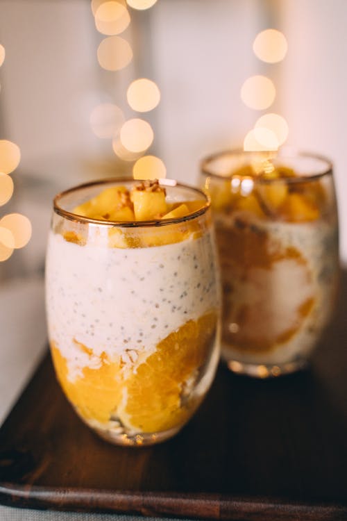 Glasses of Mango and Orange Chia Pudding on Wooden Tray