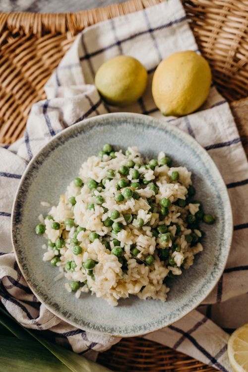 Free A plate of green pea risotto served on a plaid picnic blanket with fresh lemons. Stock Photo