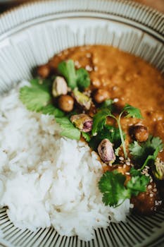 Delicious vegan curry with chickpeas and rice garnished with cilantro and pistachios.