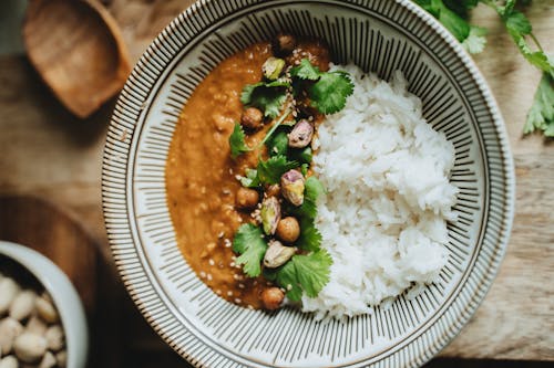 Free Delicious vegan rice bowl featuring lentil curry, topped with pistachios, cilantro, and sesame seeds. Stock Photo