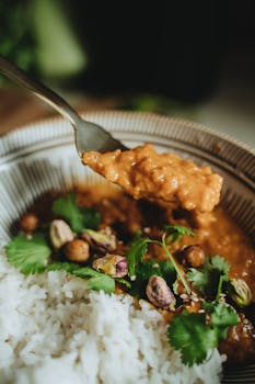 Delicious vegan curry served with rice and garnished with cilantro and pistachios.
