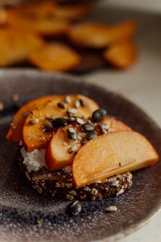 Delicious persimmon toast topped with seeds and cheese for a healthy breakfast option.
