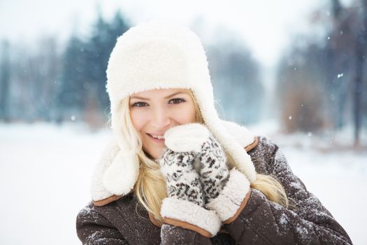 Portrait of a smiling woman in winter clothing outdoors during snowy day.