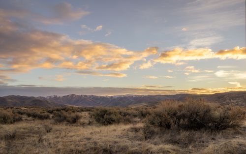 Free Scenic landscape of cloudy sunset sky over dry grassy terrain surrounded by hills in countryside Stock Photo