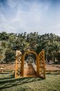 Elegant golden arbor and guest benches arranged in verdant park venue for solemn wedding ceremony