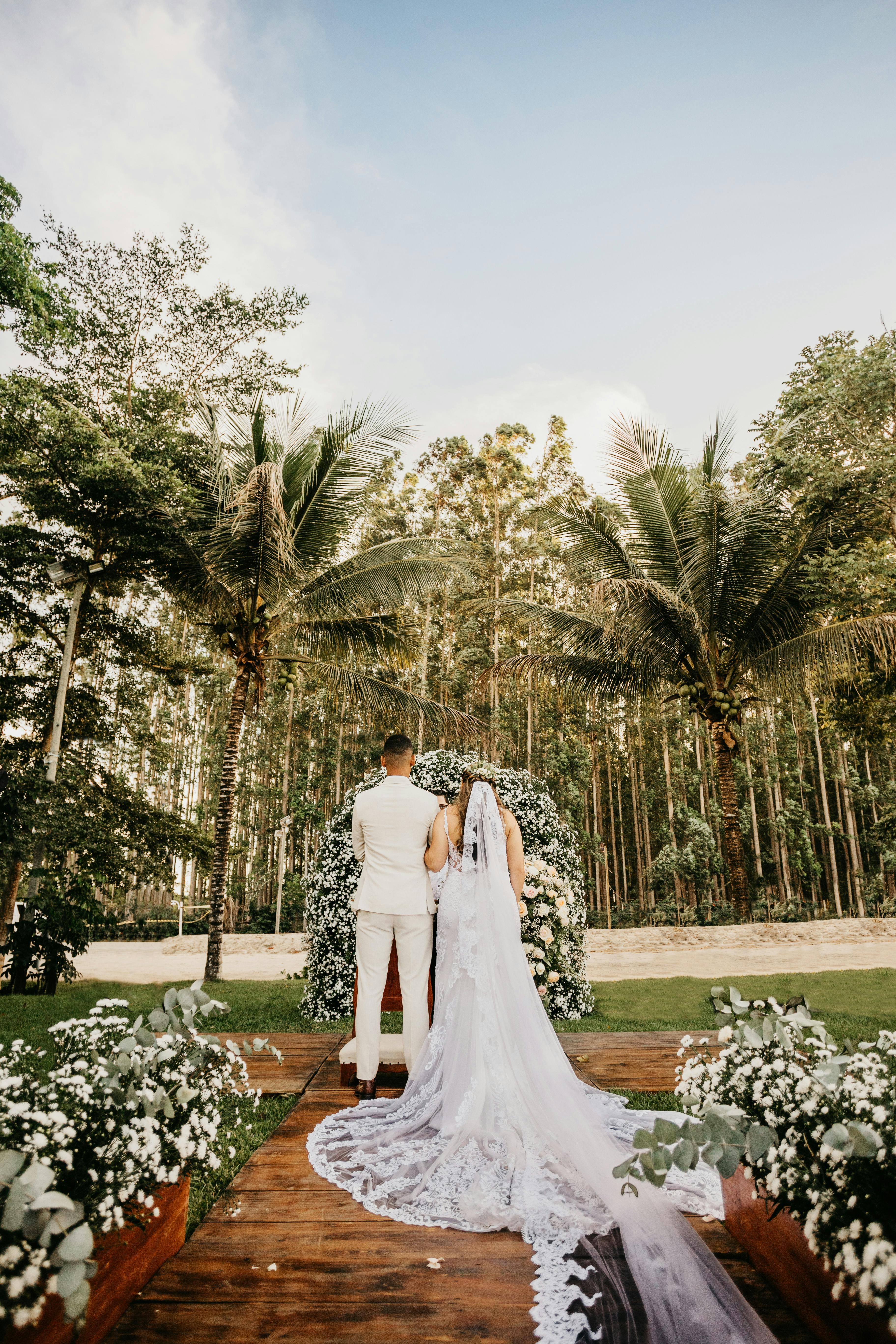 Free Unrecognizable elegant couple standing near floral arbor during wedding ceremony Stock Photo