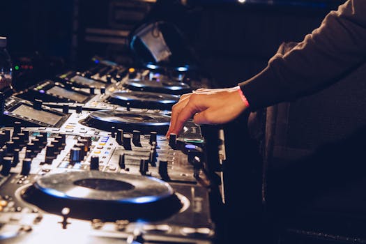 A DJ adjusting knobs on a sound mixer to produce electronic music in a vibrant nightclub setting.