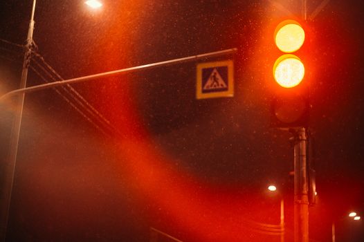 A dramatic red traffic light on a rainy night creates a striking urban scene.