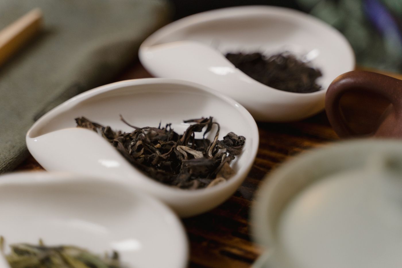 Several loose teas displayed in porcelain dishes during a tea tasting.