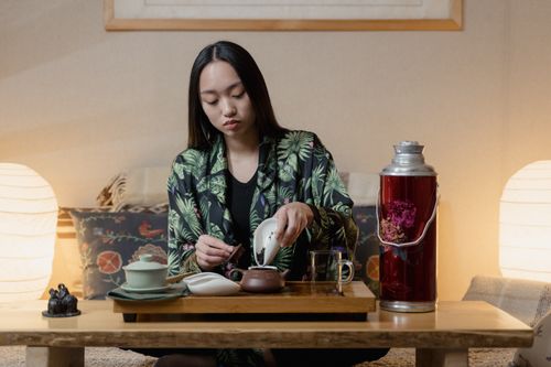 Free Woman performing a traditional tea ceremony indoors, creating a calm atmosphere. Stock Photo