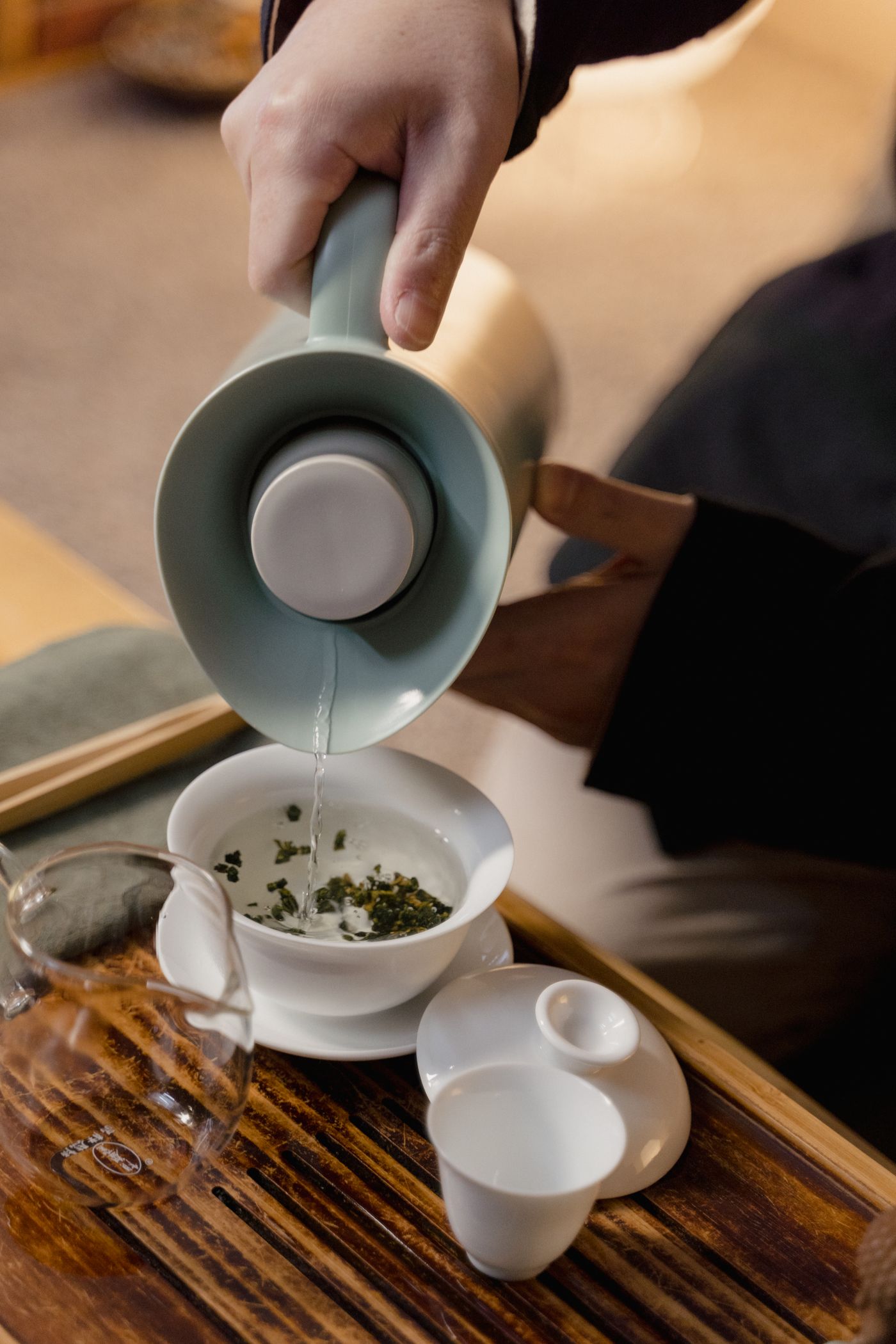 Hot water being poured into a cup with loose tea leaves.