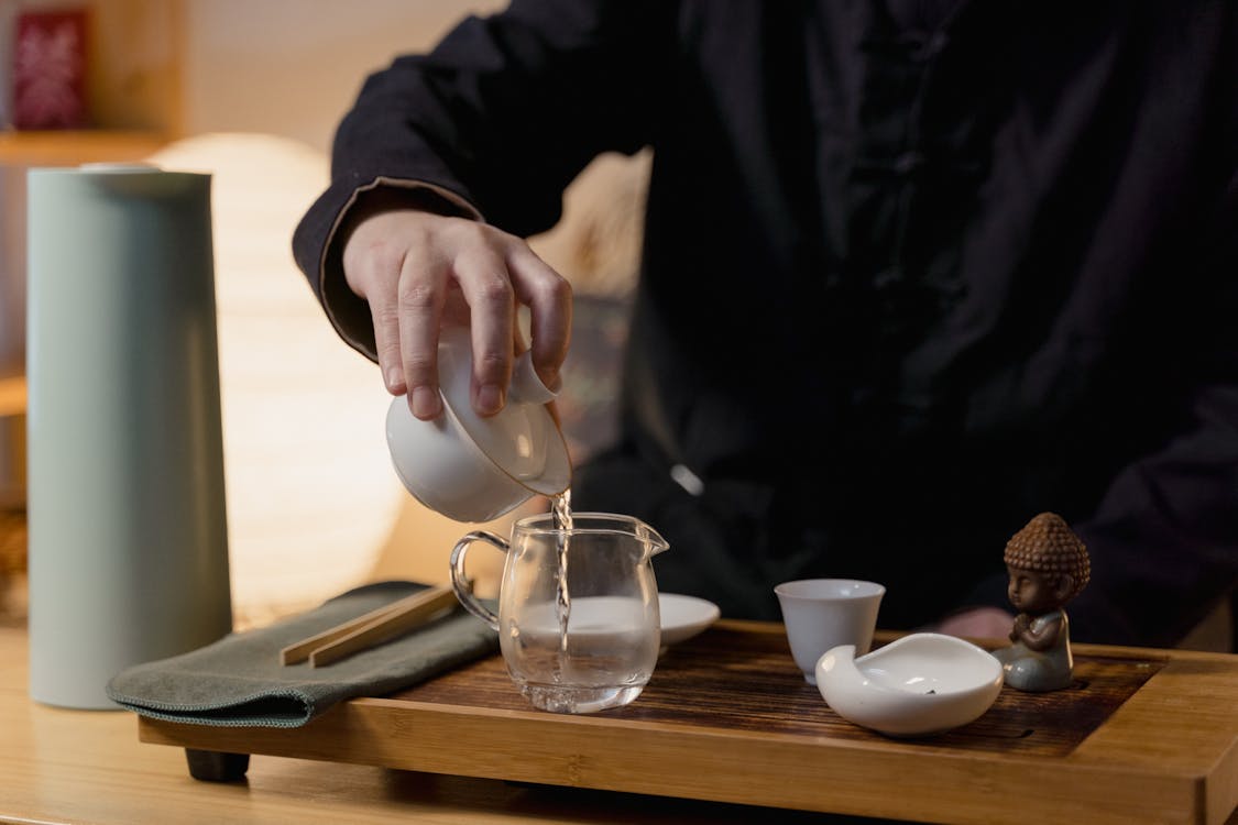 Person Pouring Water in Glass Teapot on Tea Ceremony