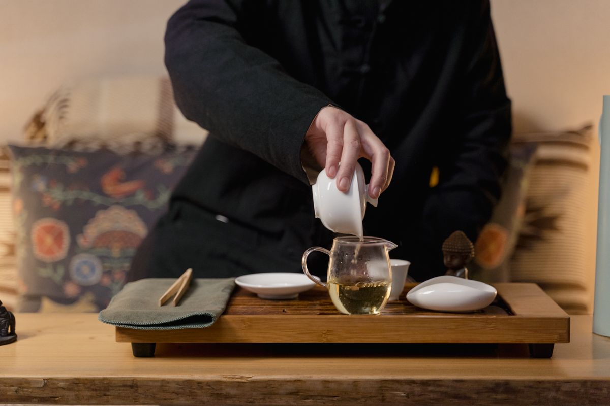 Person carefully pouring tea into a glass vessel during a ceremony