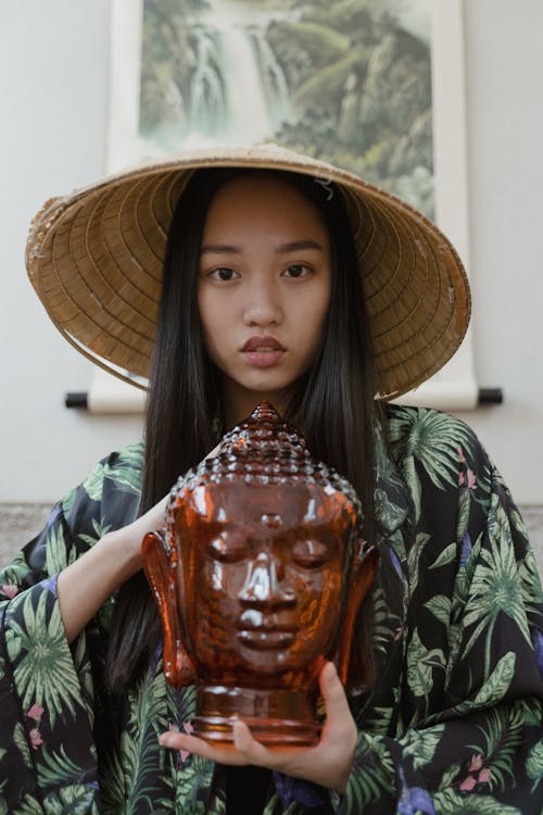 Free Woman in Conical Hat Holding Buddha Head Stock Photo