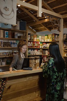 Woman customer interacting at a wood-accented store checkout, surrounded by various merchandise.