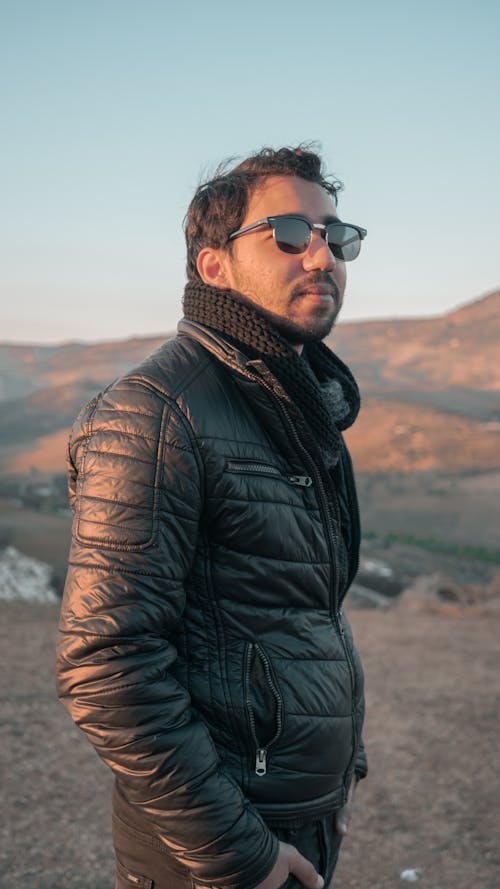 Man in Black Leather Jacket Wearing Black Sunglasses by a Hillside