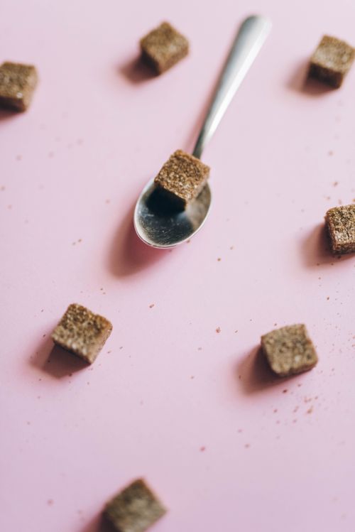Free A creative flat lay of brown sugar cubes with a spoon on a pink background for food styling. Stock Photo