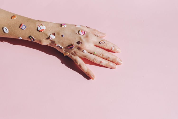 Hand Covered With Stickers On A Pink Background