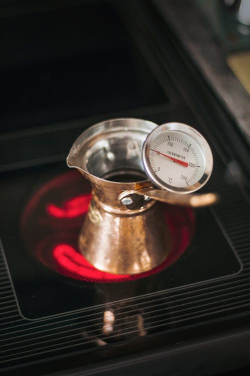Cezve with thermometer on hot stove