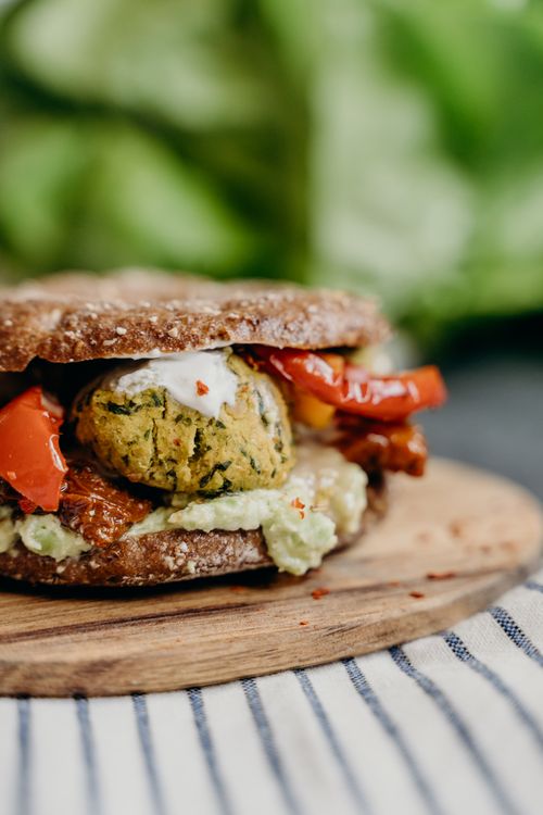 Free A close-up of a delicious vegan falafel burger with fresh vegetables on a rustic wooden plate. Stock Photo