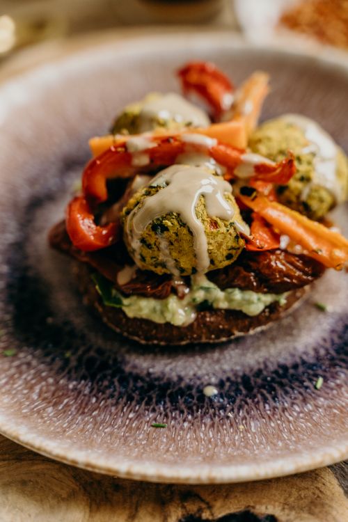 Free Savory vegan falafel dish topped with creamy tahini and roasted vegetables, perfect for a healthy meal. Stock Photo