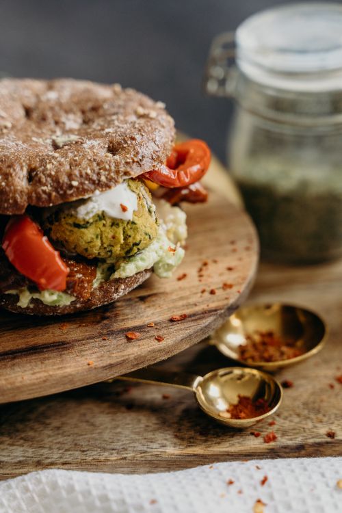 Free Delicious vegan burger with falafel and red peppers on a wooden board, perfect for a healthy meal. Stock Photo