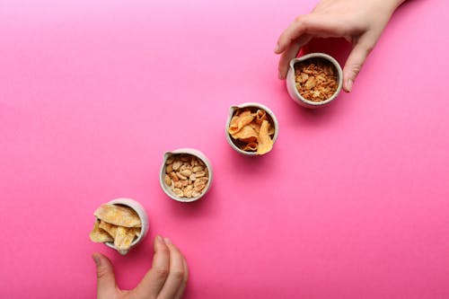 Free Crop people taking bowls with dried fruits Stock Photo