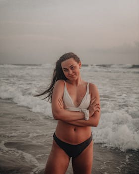 A young woman in a swimsuit poses confidently on the beach at Surfers Paradise, Australia during sunset.