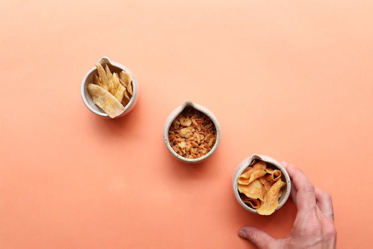 Man Taking Bowl Of Chips Placed Near Dried Fruits