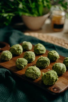 Freshly prepared green herb falafel on a wooden board, perfect for healthy vegan meals.