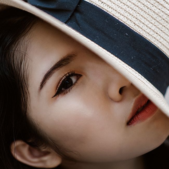 Close-up portrait of a woman with a stylish hat, emphasizing elegance and mystery.