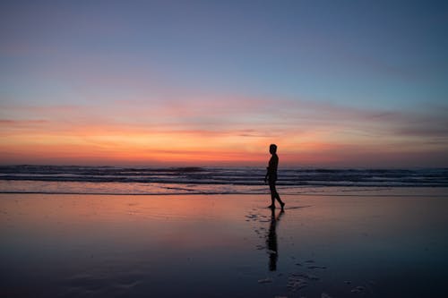 Unrecognizable man enjoying sunset on beach · Free Stock Photo