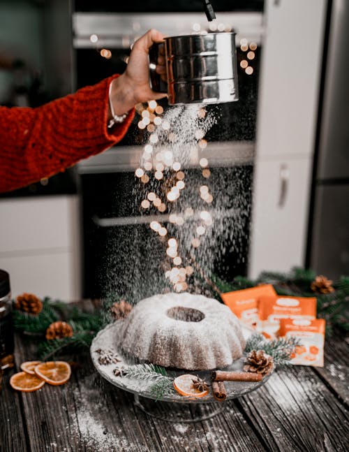 


A Person Dusting Powdered Sugar on a Cake